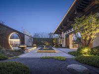 a yard area with two stone sculptures and trees around the perimeters and walkway lights