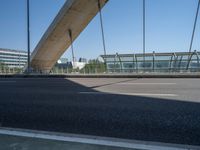 a truck driving across a bridge near a street corner near buildings and a bridge with many cables