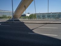 a truck driving across a bridge near a street corner near buildings and a bridge with many cables