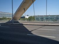 a truck driving across a bridge near a street corner near buildings and a bridge with many cables