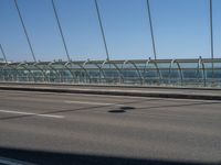 a truck driving across a bridge near a street corner near buildings and a bridge with many cables