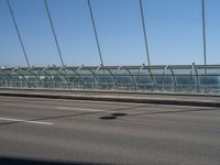 a truck driving across a bridge near a street corner near buildings and a bridge with many cables