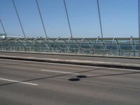 a truck driving across a bridge near a street corner near buildings and a bridge with many cables