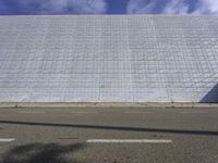 a stop sign at the top of a white brick wall near a road and a building