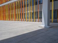 a concrete structure made into rows of orange and yellow poles are on a cement sidewalk