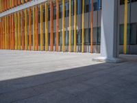 a concrete structure made into rows of orange and yellow poles are on a cement sidewalk