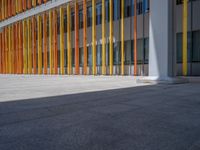 a concrete structure made into rows of orange and yellow poles are on a cement sidewalk