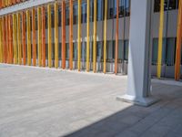 a concrete structure made into rows of orange and yellow poles are on a cement sidewalk