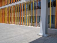 a concrete structure made into rows of orange and yellow poles are on a cement sidewalk