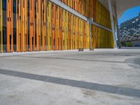 a concrete structure made into rows of orange and yellow poles are on a cement sidewalk