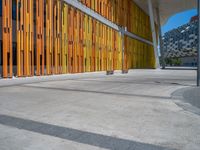 a concrete structure made into rows of orange and yellow poles are on a cement sidewalk