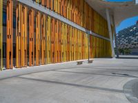 a concrete structure made into rows of orange and yellow poles are on a cement sidewalk