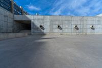 the empty parking lot in front of a wall with apartment buildings on it and a skateboarder on a ramp