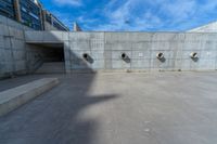 the empty parking lot in front of a wall with apartment buildings on it and a skateboarder on a ramp