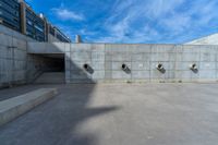 the empty parking lot in front of a wall with apartment buildings on it and a skateboarder on a ramp