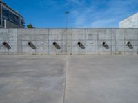 the empty parking lot in front of a wall with apartment buildings on it and a skateboarder on a ramp