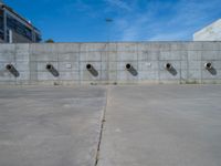 the empty parking lot in front of a wall with apartment buildings on it and a skateboarder on a ramp