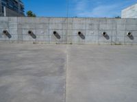 the empty parking lot in front of a wall with apartment buildings on it and a skateboarder on a ramp