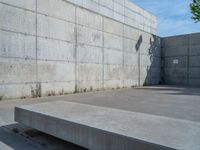 the empty parking lot in front of a wall with apartment buildings on it and a skateboarder on a ramp