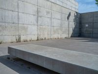 the empty parking lot in front of a wall with apartment buildings on it and a skateboarder on a ramp