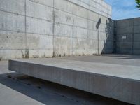 the empty parking lot in front of a wall with apartment buildings on it and a skateboarder on a ramp