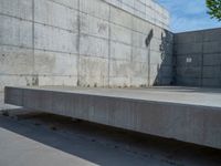 the empty parking lot in front of a wall with apartment buildings on it and a skateboarder on a ramp