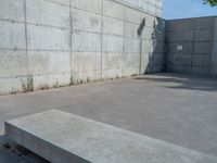 the empty parking lot in front of a wall with apartment buildings on it and a skateboarder on a ramp