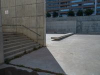 the empty parking lot in front of a wall with apartment buildings on it and a skateboarder on a ramp