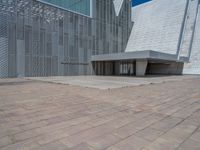 a white building with several steps and large glass panels in the facade is a mosaic that depicts a man