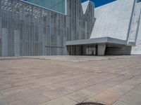 a white building with several steps and large glass panels in the facade is a mosaic that depicts a man