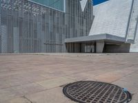 a white building with several steps and large glass panels in the facade is a mosaic that depicts a man