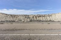 the road is empty and there are many rocks on both sides of the hill in front of it