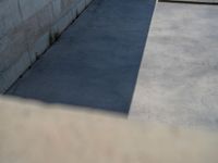 the empty parking lot in front of a wall with apartment buildings on it and a skateboarder on a ramp