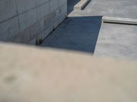 the empty parking lot in front of a wall with apartment buildings on it and a skateboarder on a ramp