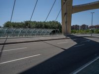 a truck driving across a bridge near a street corner near buildings and a bridge with many cables