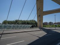 a truck driving across a bridge near a street corner near buildings and a bridge with many cables