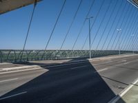 a truck driving across a bridge near a street corner near buildings and a bridge with many cables