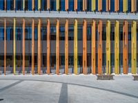 a concrete structure made into rows of orange and yellow poles are on a cement sidewalk