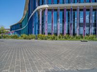 a building with pink glass and purple striped exterior is shown with the brick path on the left