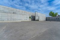 the empty parking lot in front of a wall with apartment buildings on it and a skateboarder on a ramp