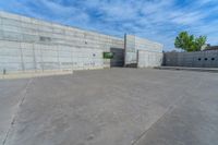 the empty parking lot in front of a wall with apartment buildings on it and a skateboarder on a ramp