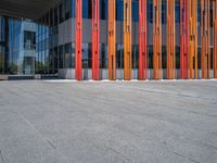 a concrete structure made into rows of orange and yellow poles are on a cement sidewalk