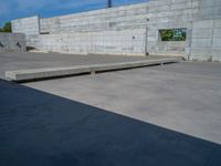 the empty parking lot in front of a wall with apartment buildings on it and a skateboarder on a ramp