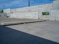 the empty parking lot in front of a wall with apartment buildings on it and a skateboarder on a ramp