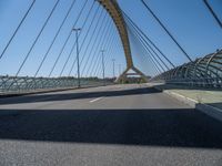 a truck driving across a bridge near a street corner near buildings and a bridge with many cables