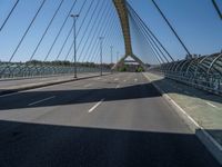 a truck driving across a bridge near a street corner near buildings and a bridge with many cables