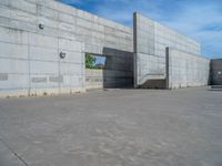 the empty parking lot in front of a wall with apartment buildings on it and a skateboarder on a ramp