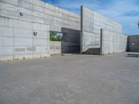 the empty parking lot in front of a wall with apartment buildings on it and a skateboarder on a ramp