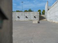 the empty parking lot in front of a wall with apartment buildings on it and a skateboarder on a ramp