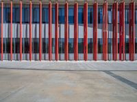 a concrete structure made into rows of orange and yellow poles are on a cement sidewalk